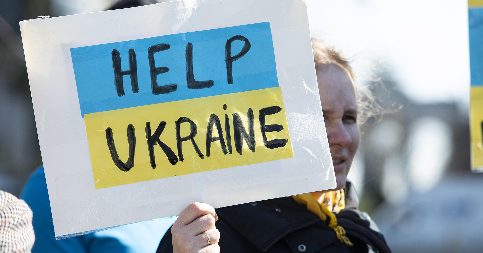 Woman holds up sign with words "Help Ukraine"