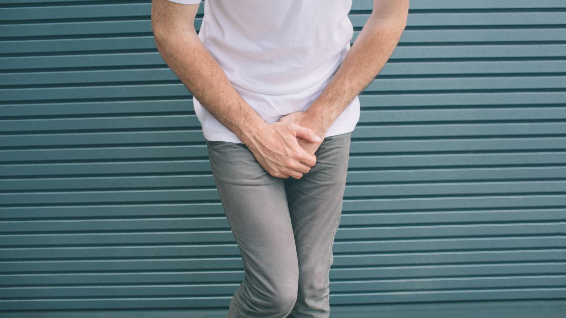 Cut view of man covering urine with hands. He has some pain and problem. Isolated on striped and blue background