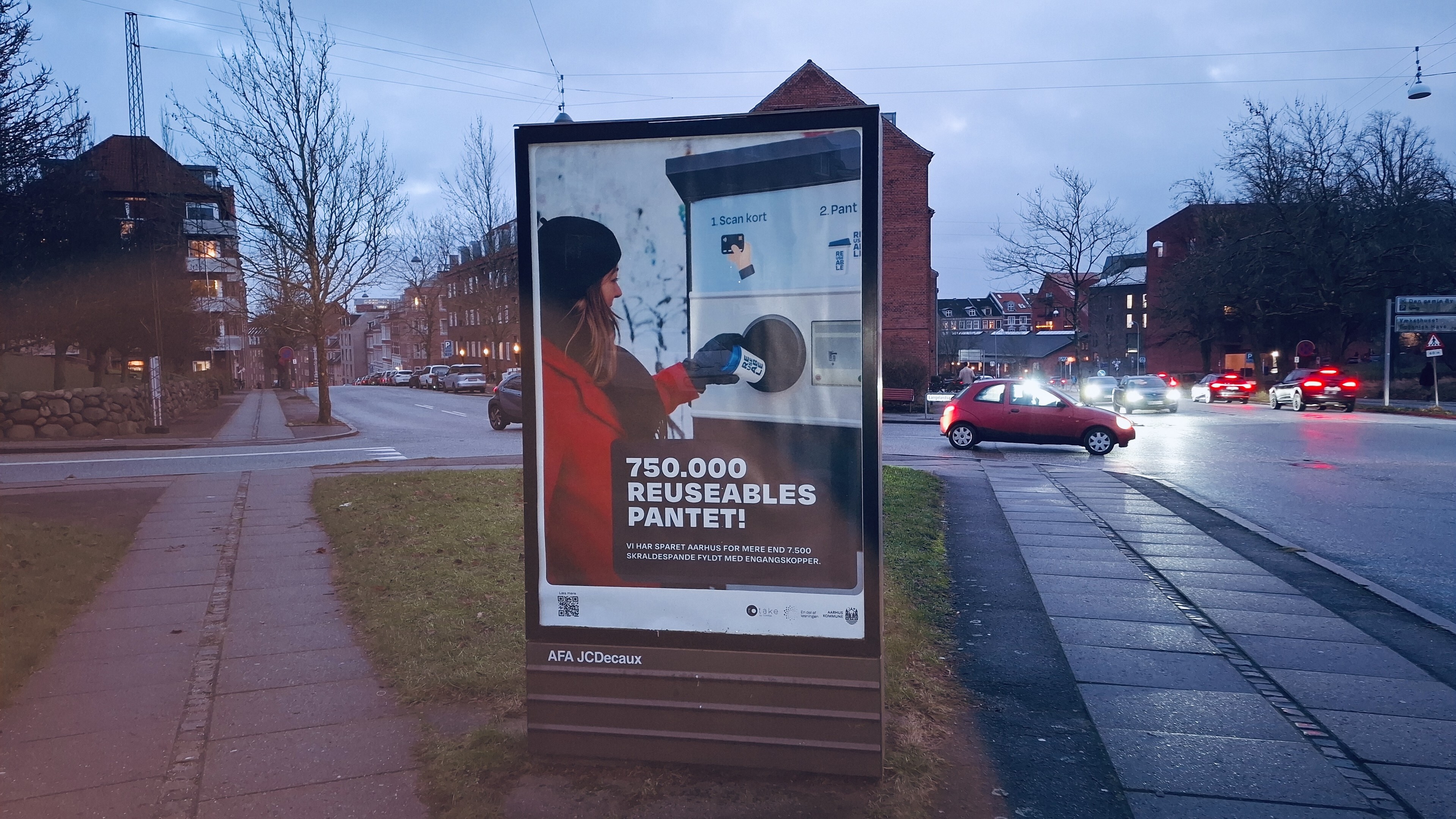 A council poster on a road in Aarhus, Denmark, cars and bikes and houses in the background. The photo is of someone putting a cup back into one of the Resuable depost machines. The Danish headline, translated: '750,000 reusable cups deposited'. Before someone nitpicks: No, the machines don't give cash back. Apart from that, they are pretty universally user-friendly - you just contactlessly wave your bank card at the machine (or your bank app on your phone, if you have one) and your money gets put back in. There are machines on public streets and indoors at locations like the library cafe. 