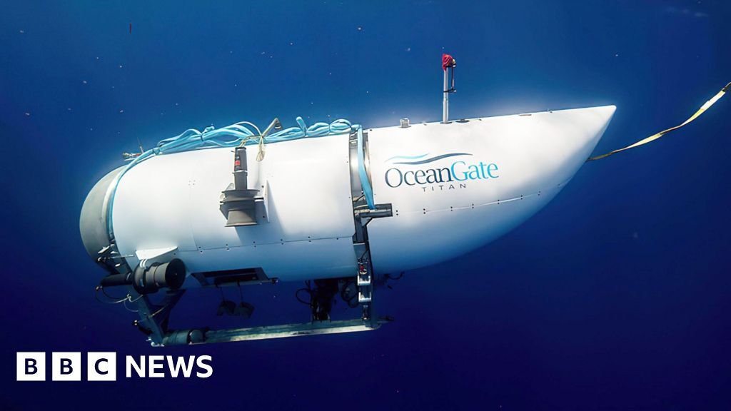 A submersible vessel with the name OceanGate written on its side is seen underwater.