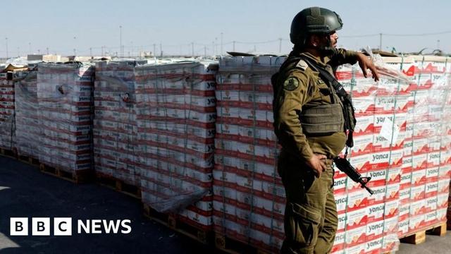 An Israeli soldier stands next to the parcels of humanitarian aid