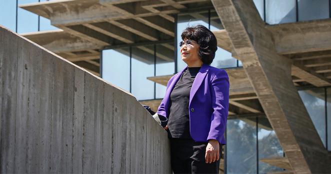 Woman in a purple suit standing outside.