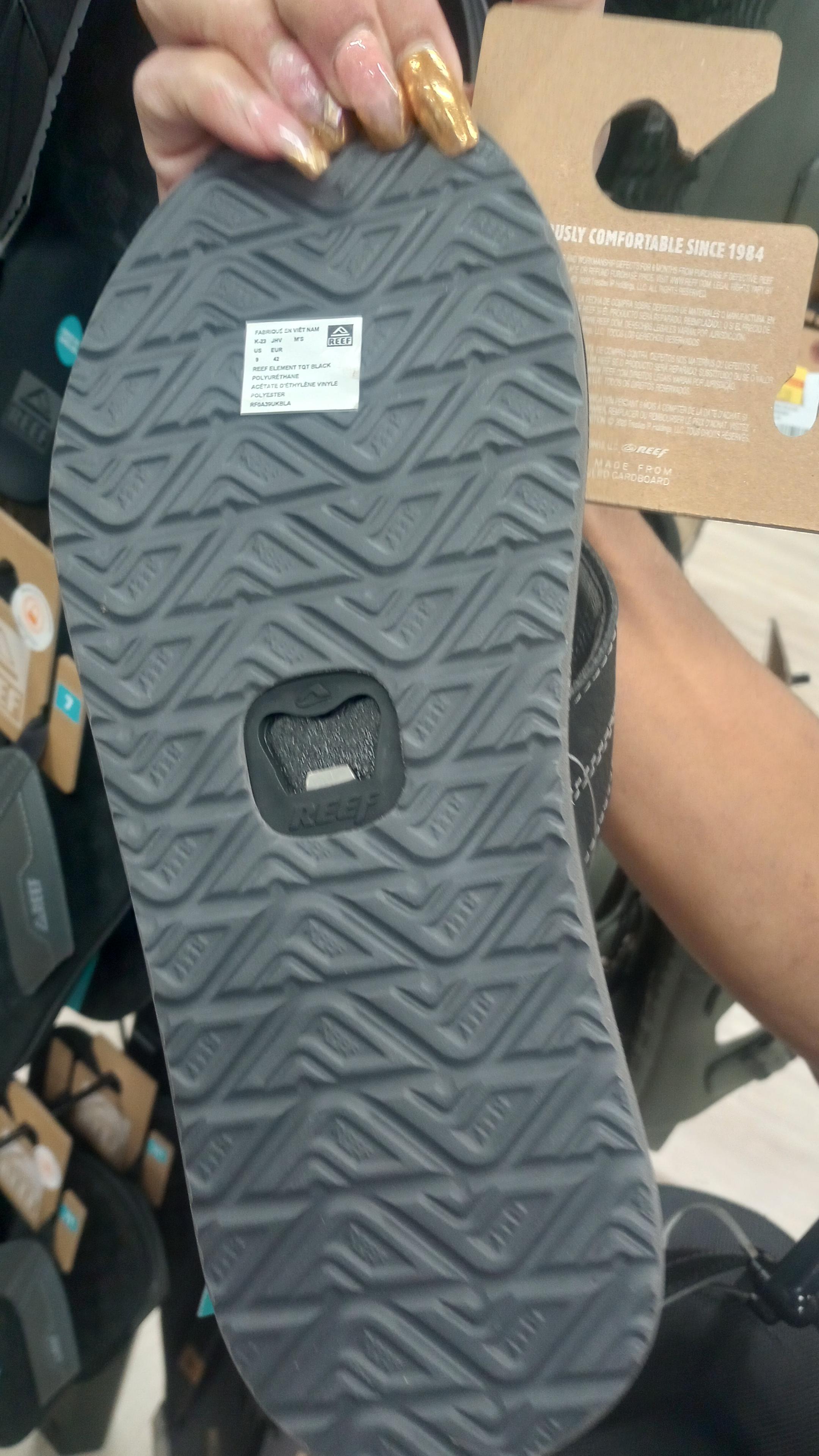 The bottom sole of a sandal with a bottle opener in the center of it.