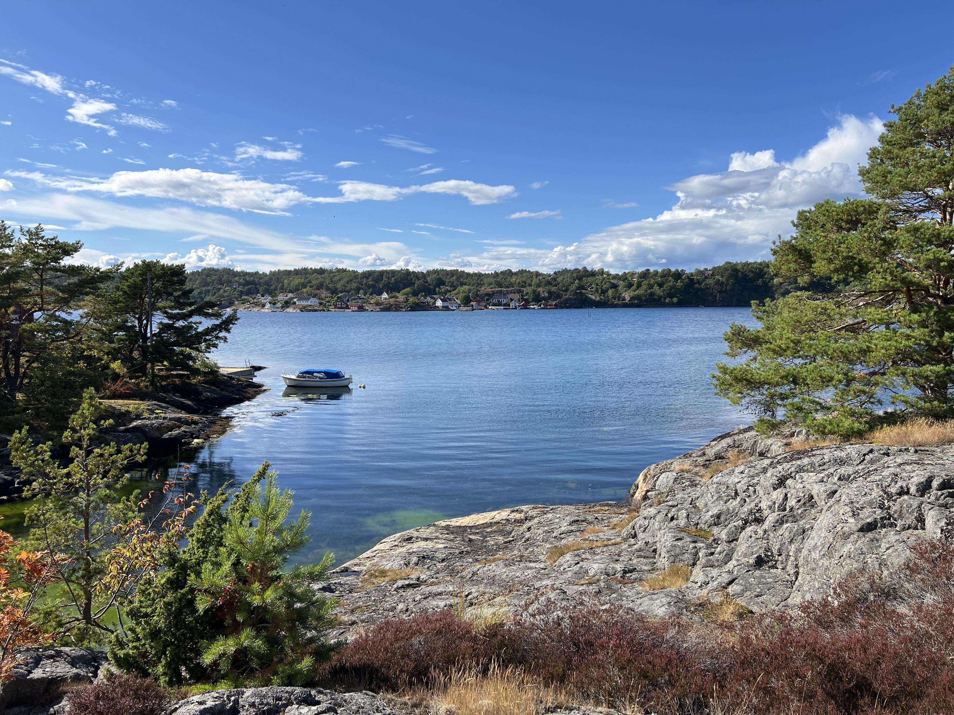 Coastal view on a sunny day from the Norwegian island of Flostaøya. A boat is floating in the foreground.