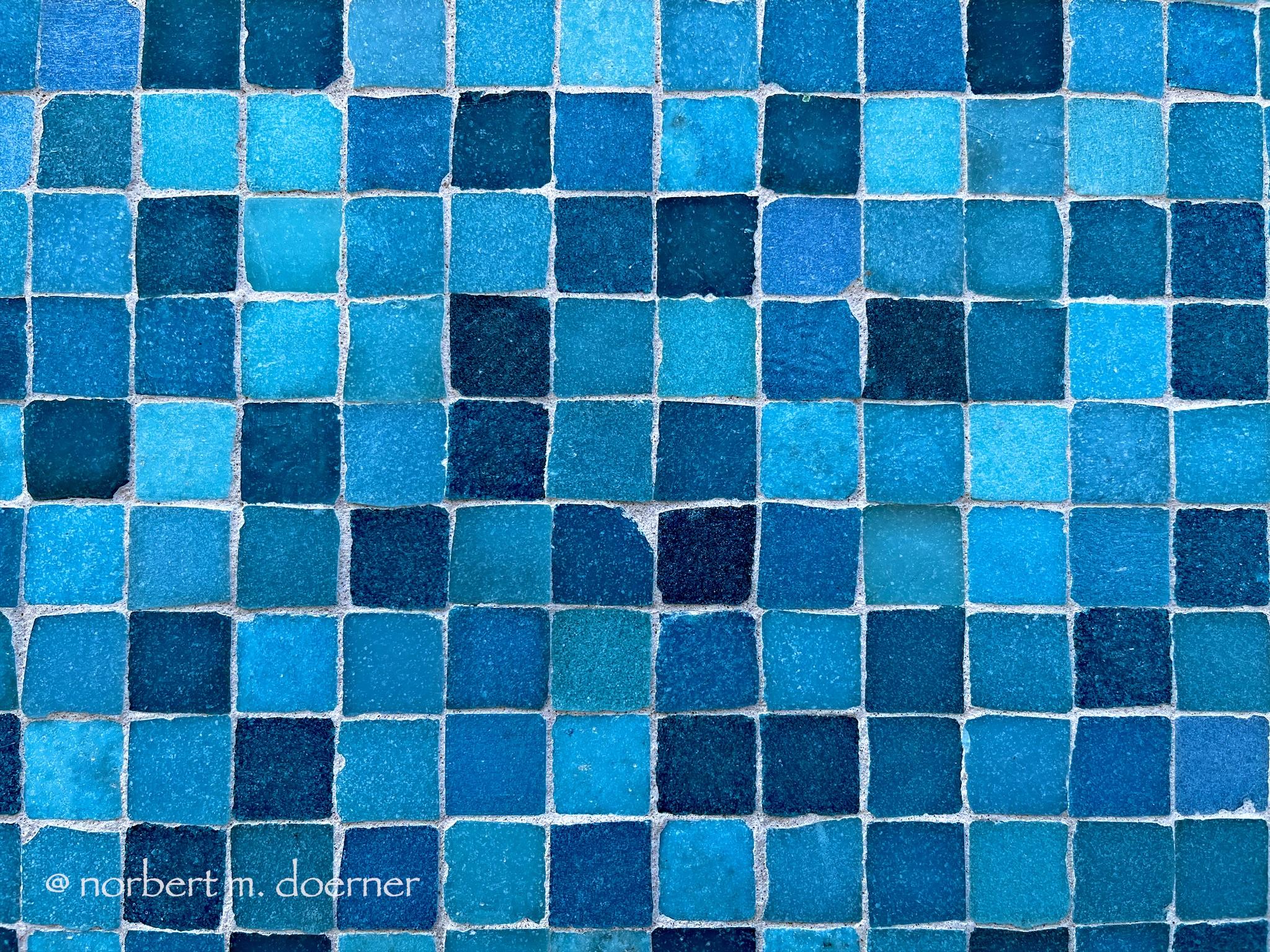 Quadratische Steinchen in mehreren Blautönen geformt zu einem Mosaik, Frontalansicht